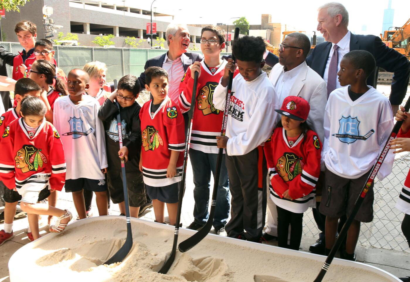 Mayor Rahm Emanuel pals around with Blackhawks CEO John McDonough as children use hockey sticks instead of shovels to break ground on the new training facility and community center.