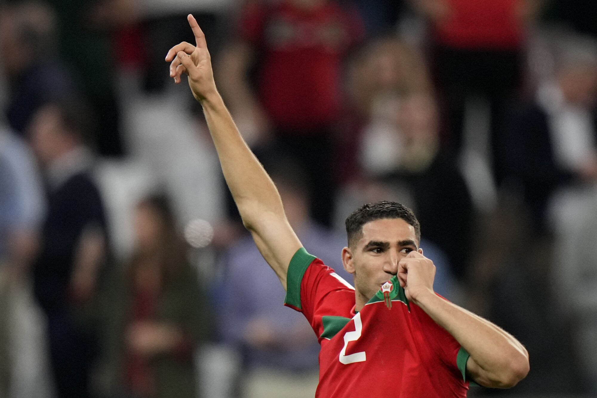 Morocco's Achraf Hakimi celebrates by kissing the crest on his jersey after hitting the winning penalty kick against Spain
