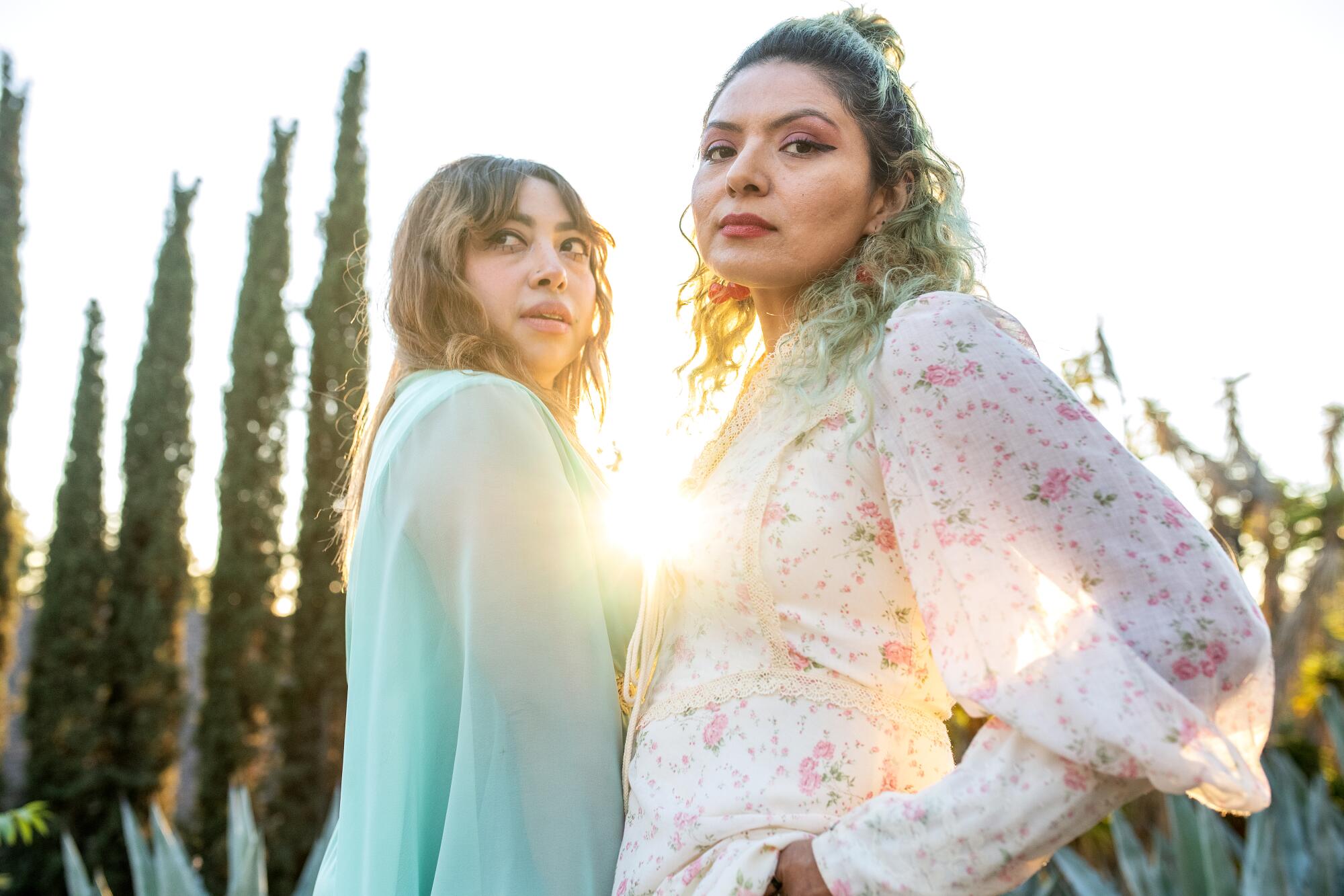 Sisters Ursula and Rebecca Recinos, wearing flowing, flowery dresses.