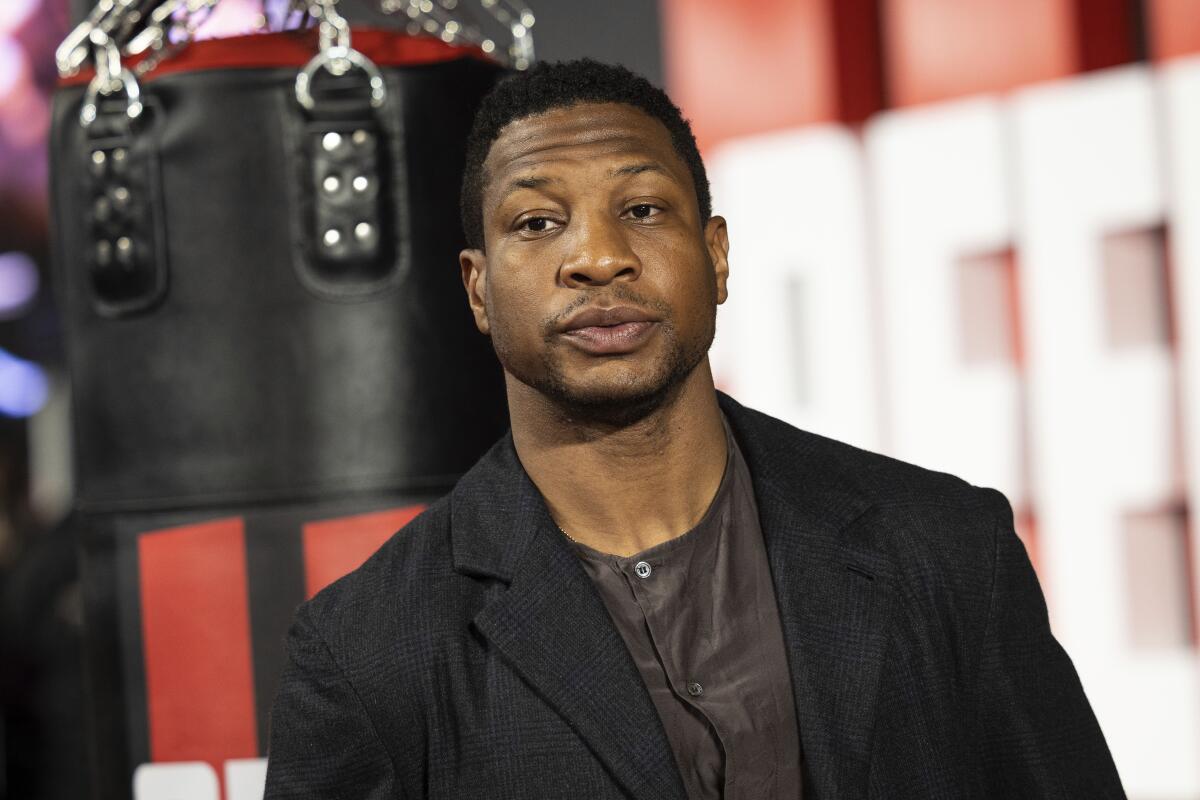 Jonathan Majors at a movie premiere in a black blazer and a gray shirt