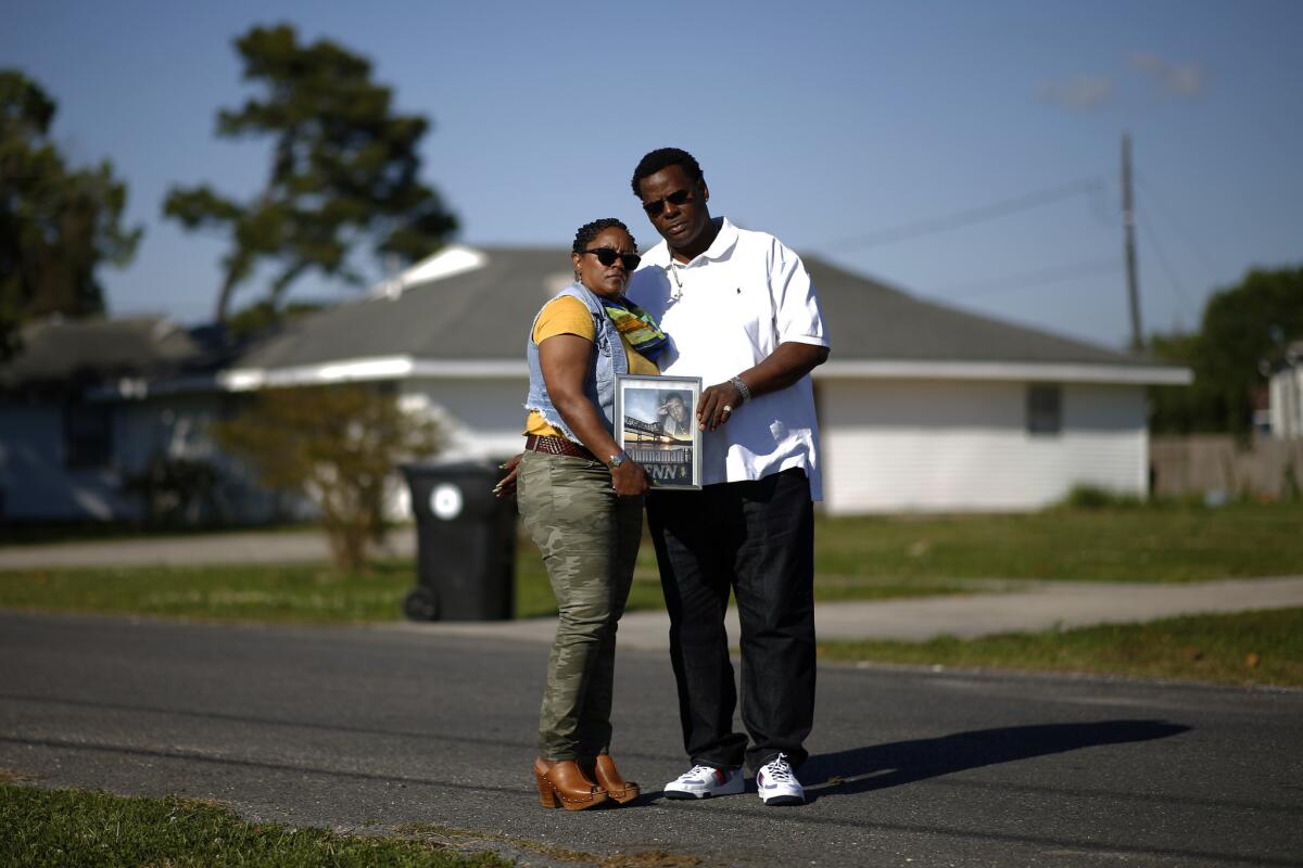 Deidra Smoot-Hall and Kenneth Hall Sr. with a photo of their son, Kenneth Hall Jr., at the site where he was shot to death in 2015.