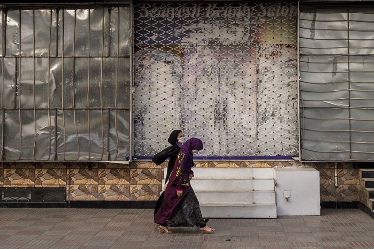 Afghan women walk past a closed beauty salon in Kabul on Saturday.