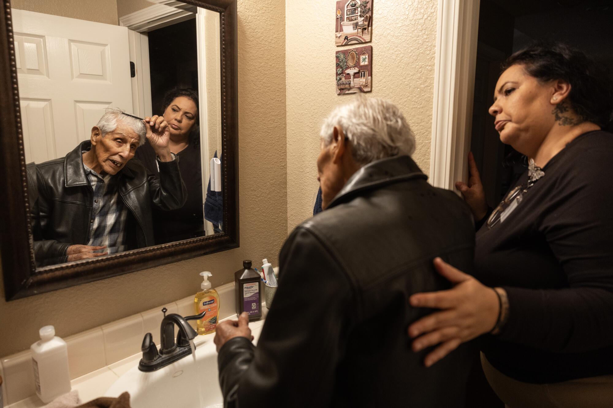 Caretaker Maria Dominguez helps Bob Fernandez get ready before a morning walk in Lodi, Calif.