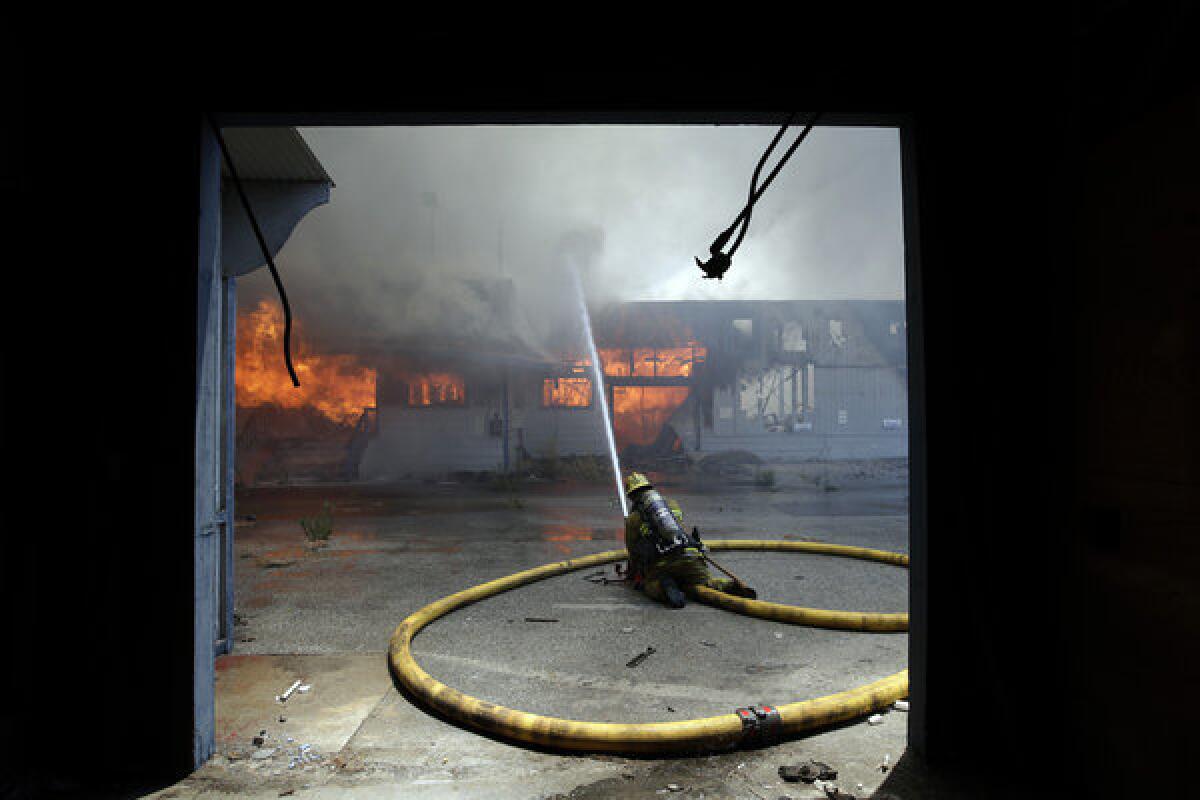 A firefighter sprays water on a burning warehouse in City of Industry.