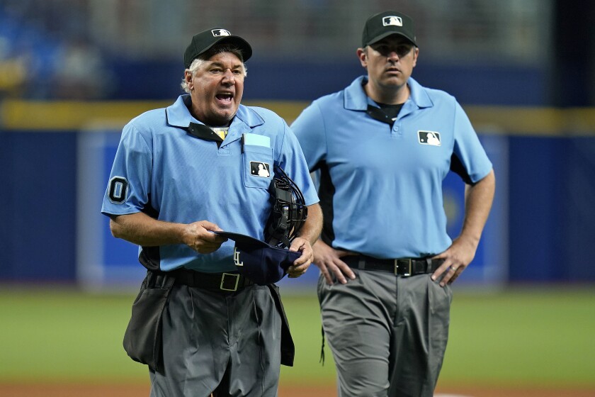 Home plate umpire Tom Hallion, left, makes Tampa Bay Rays relief pitcher Diego Castillo change his hat during the ninth inning of a baseball game Wednesday, June 23, 2021, in St. Petersburg, Fla. Looking on is first base umpire Mark Ripperger. (AP Photo/Chris O'Meara)
