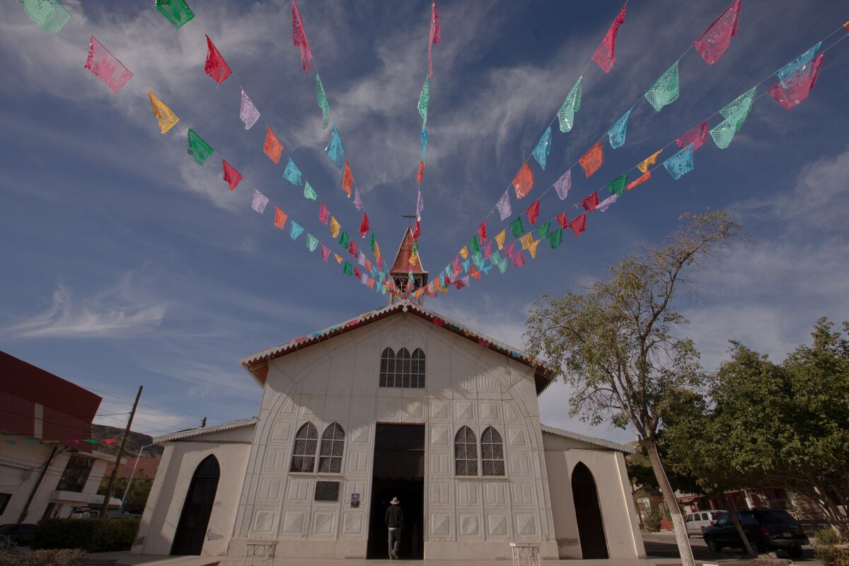 Colorful flags hang from the Iglesia de Santa Barbara, a prefab structure designed in Europe and made of metal.
