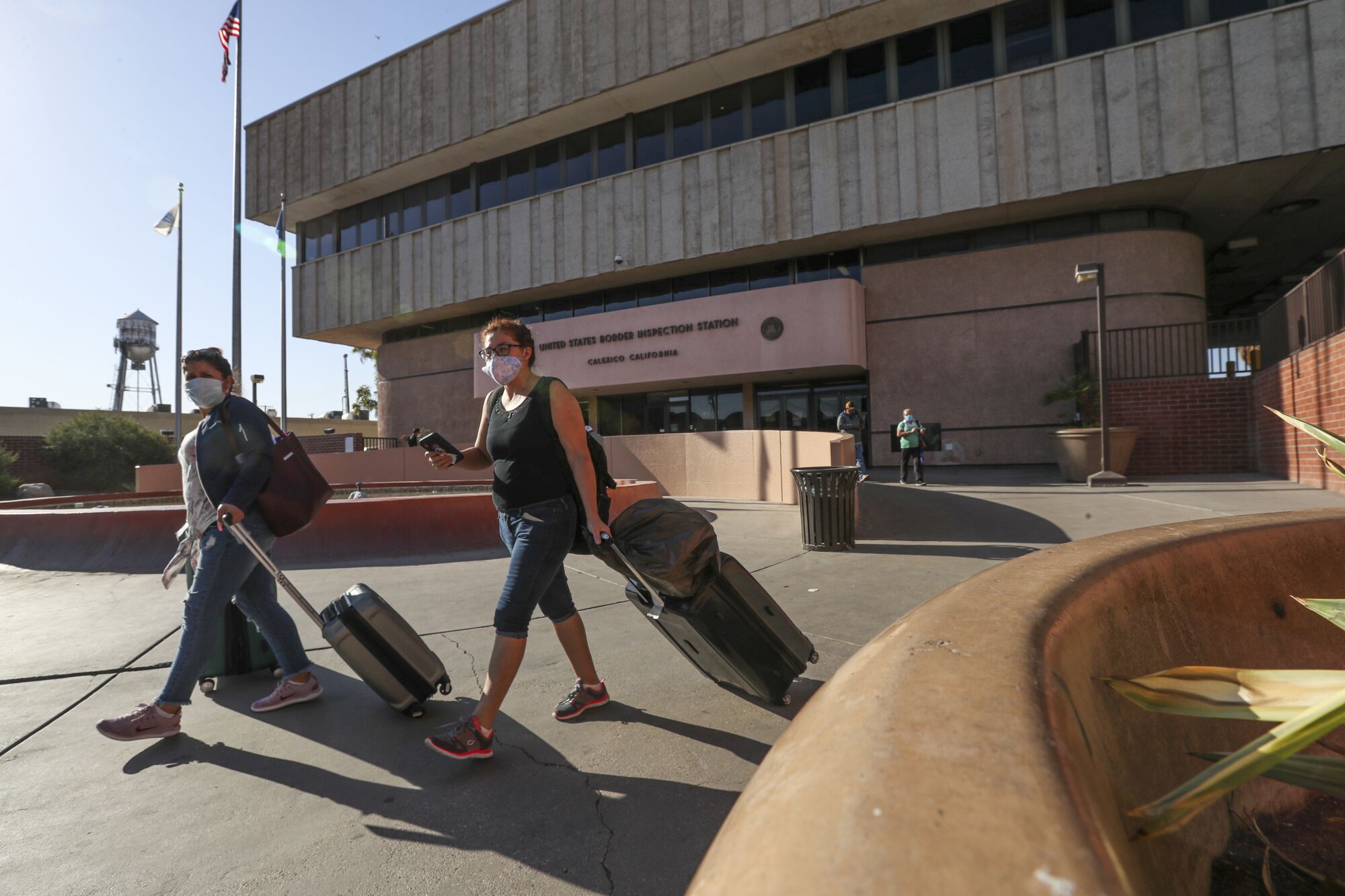 Two women wearing masks enter the United States from Mexicali at the border crossing in Calexico.