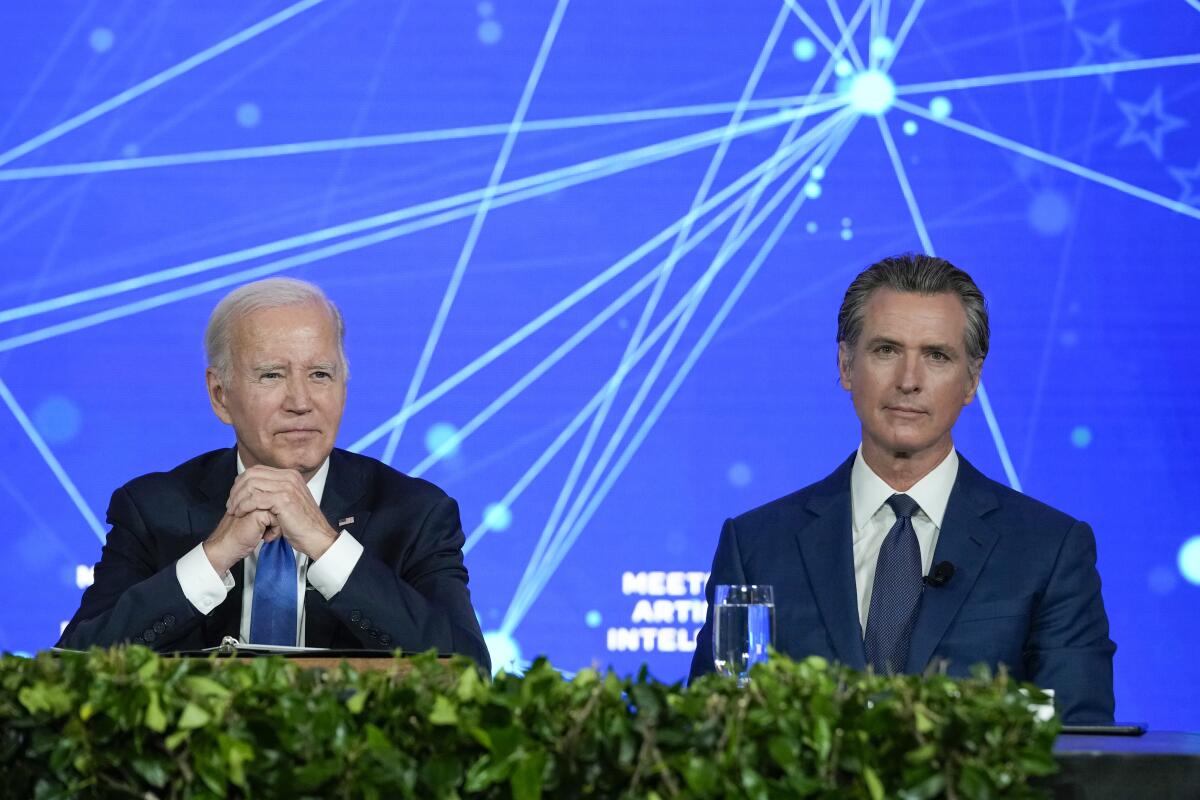 President Biden and California Gov. Gavin Newsom sitting in front of a blue background with dots and intersecting lines