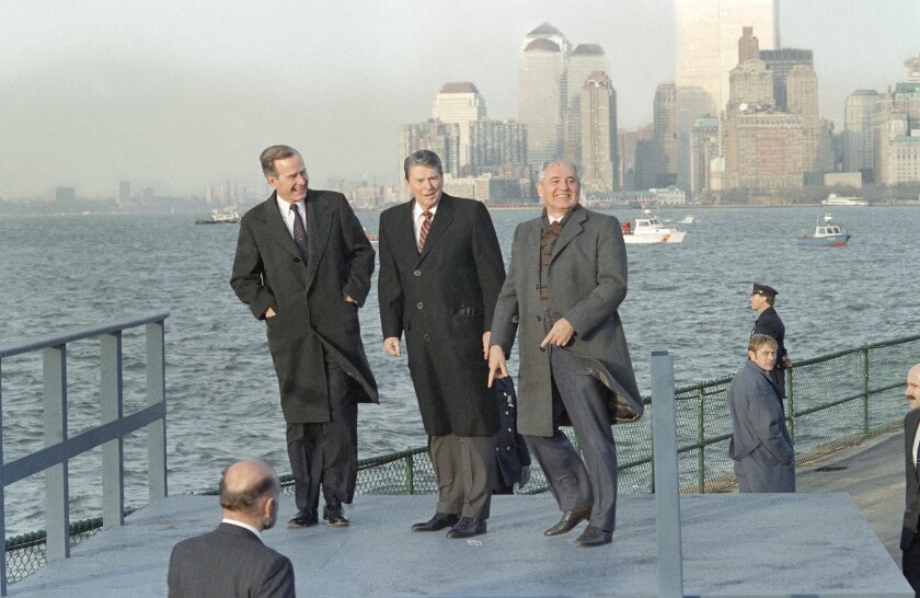 Three men stand by a waterfront.