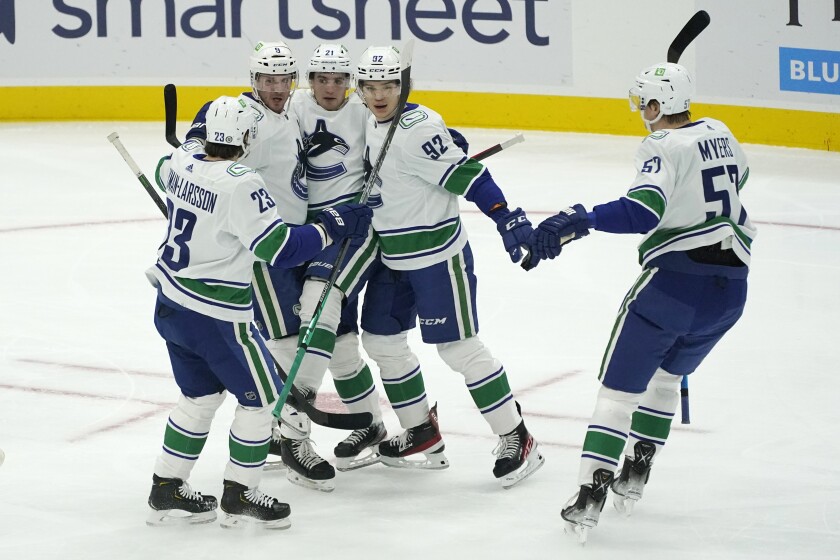 Vancouver Canucks right wing Vasily Podkolzin, second from right, is greeted by teammates after he scored a goal against the Seattle Kraken during the first period of an NHL hockey game Saturday, Jan. 1, 2022, in Seattle. (AP Photo/Ted S. Warren)