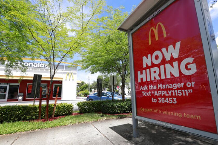 FILE - In this Monday, July 1, 2019, file photo, a "Now Hiring" sign appears on a bus stop in front of a McDonald's restaurant in Miami. Starting Wednesday, Sept. 25, 2019, McDonald’s Corp. will let job seekers start an application by using voice commands on their smartphones with Amazon’s Alexa or Google’s Assistant. (AP Photo/Wilfredo Lee, File)