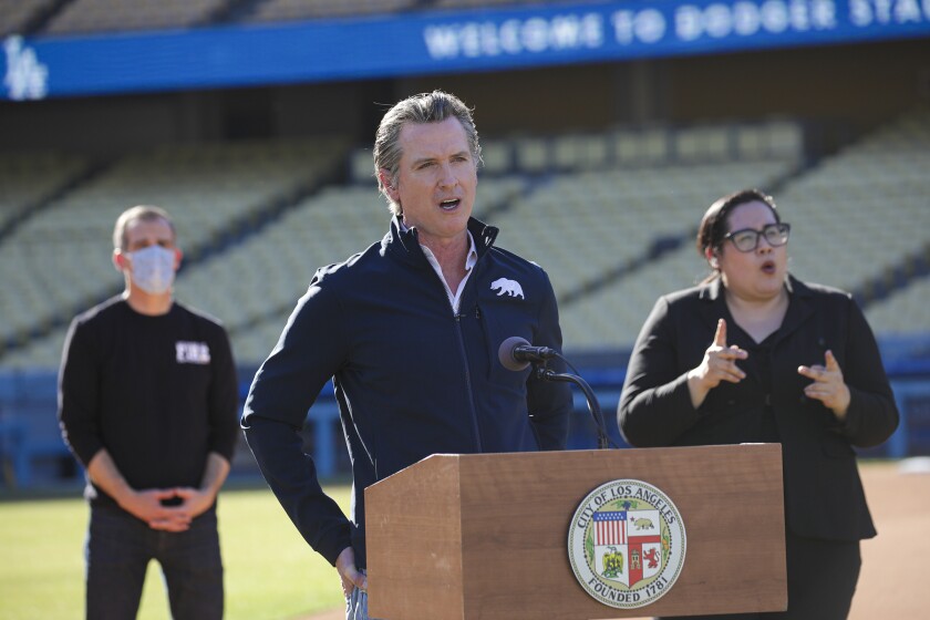 Governor Gavin Newsom addresses a press conference held at the launch of a mass COVID-19 vaccination site at Dodger Stadium, Friday, Jan. 15, 2021, in Los Angeles. Newsom and Los Angeles Mayor Eric Garcetti, left, touted the stadium as a new mass vaccination site while acknowledging they need clarity from the federal government on the availability of future vaccine supply. (Irfan Khan/Los Angeles Times via AP, Pool)