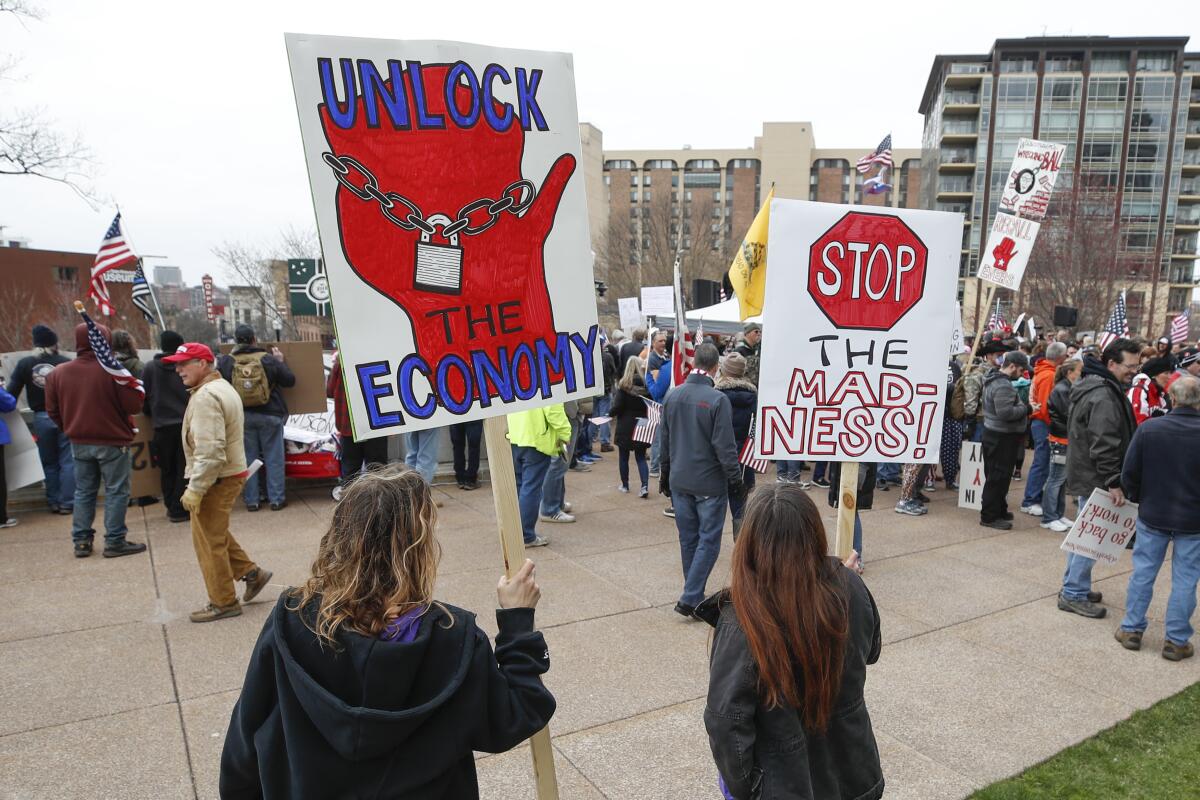Demonstrators hold signs during a protest against coronavirus-related shutdowns in Madison, Wisc., on April 24.