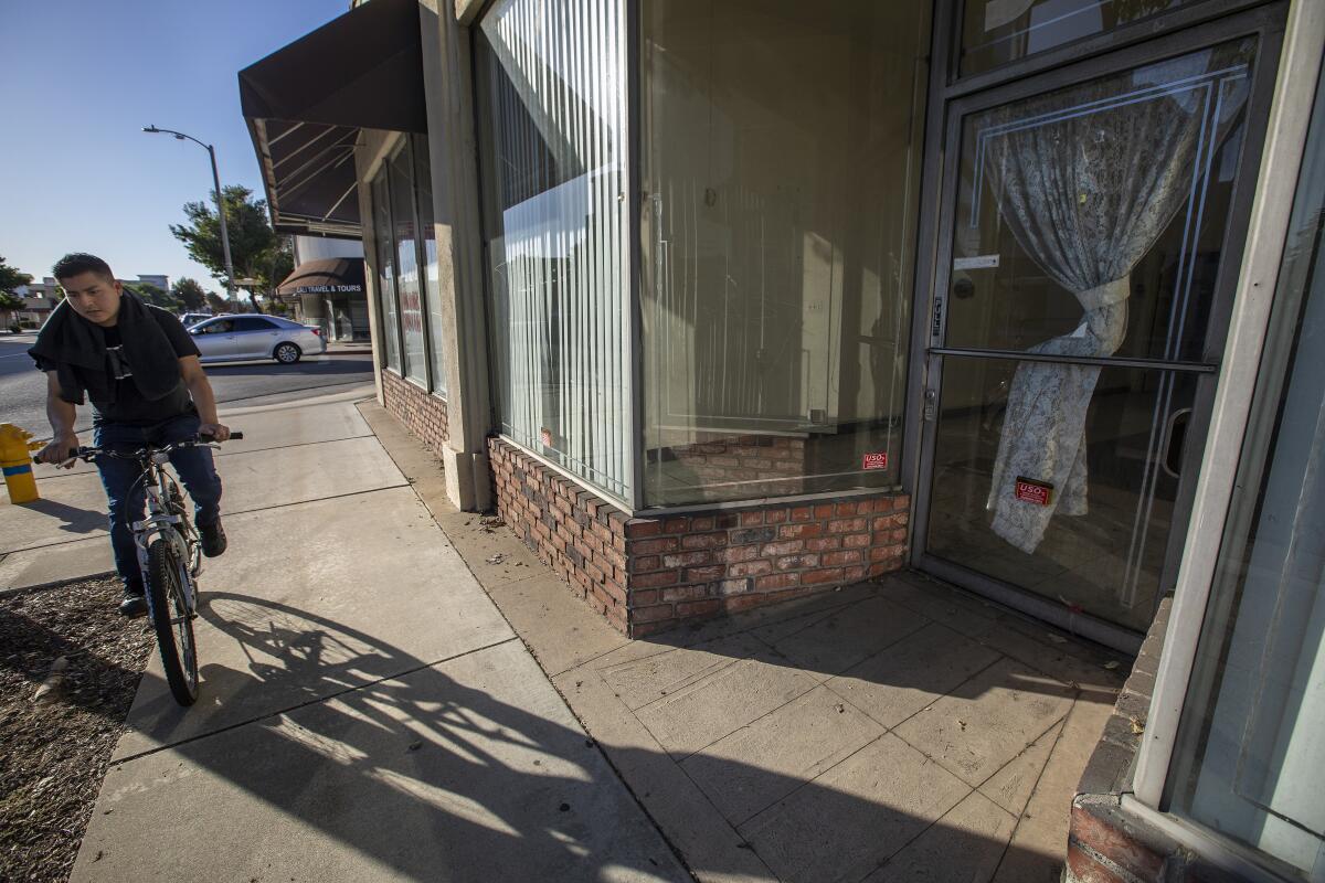 A bicycle rider pedals past a closed business, available for lease on Valley Boulevard in Rosemead.