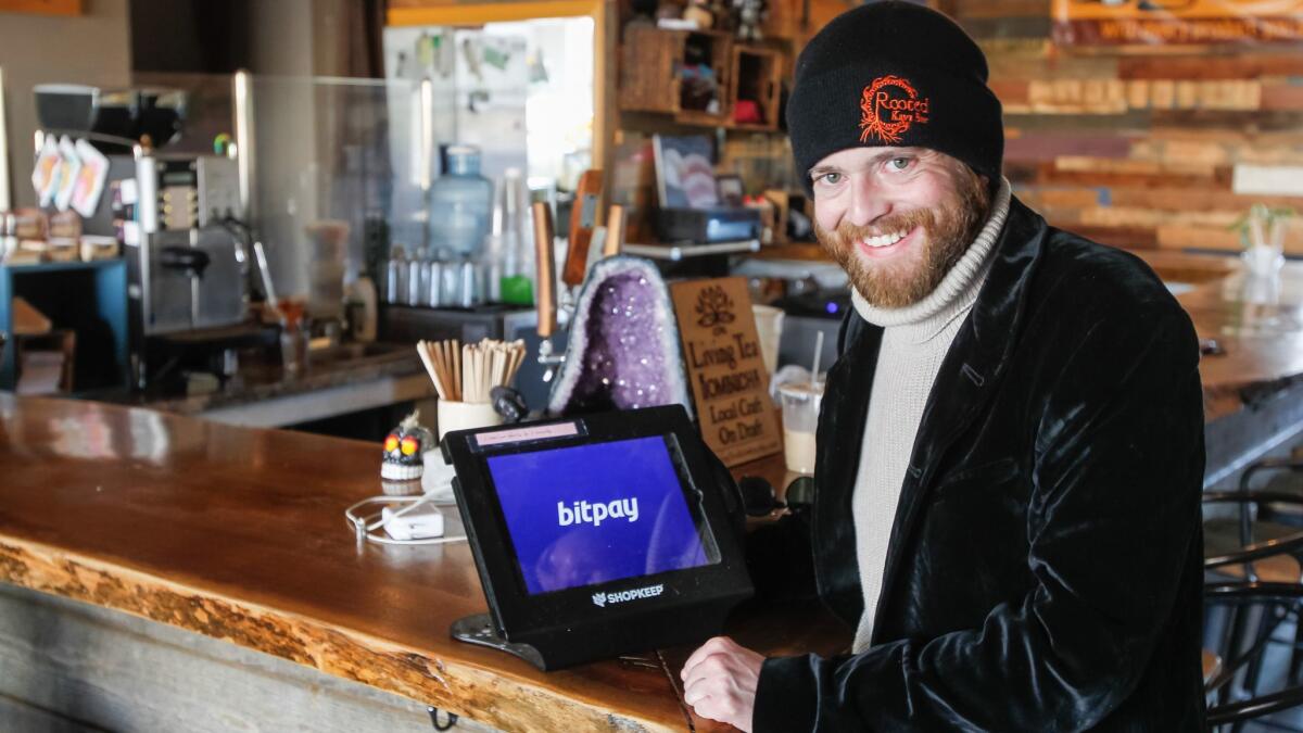 Rooted Kava Bar co-owner Dillon Chaulsett stands in his business in Hillcrest on Tuesday morning in San Diego, California. At left is a pay terminal for his business that accepts Bitcoins as a form of payment for purchases at the store.
