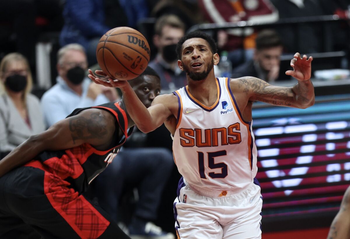 Phoenix Suns guard Cameron Payne, right, loses control of the ball as Portland Trail Blazers forward Tony Snell, left, defends during the first half of an NBA basketball game in Portland, Ore., Tuesday, Dec. 14, 2021. (AP Photo/Steve Dipaola)