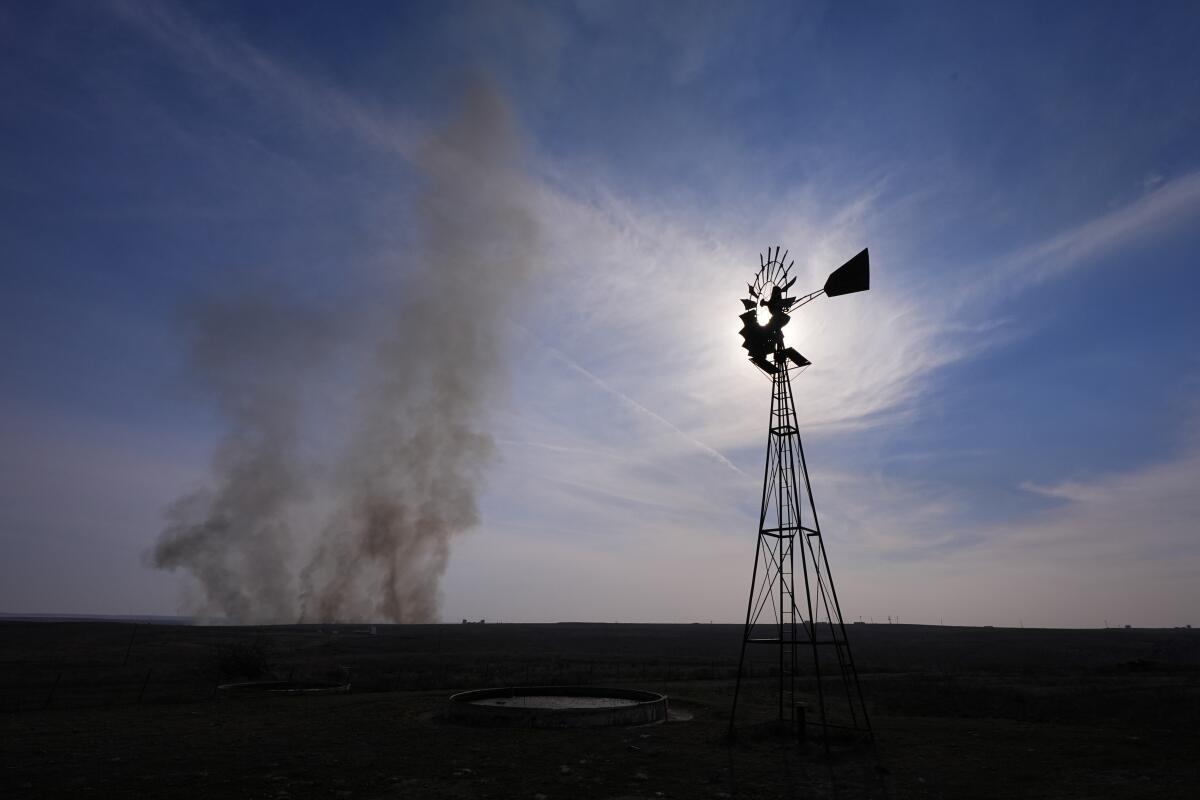 Smoke billows on a field near a windmill in Canadian, Texas.