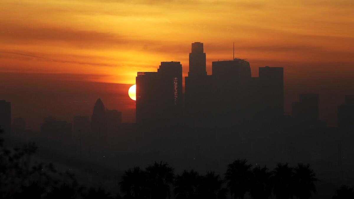 The sun sets behind the downtown Los Angeles skyline on Dec. 14, 2016.