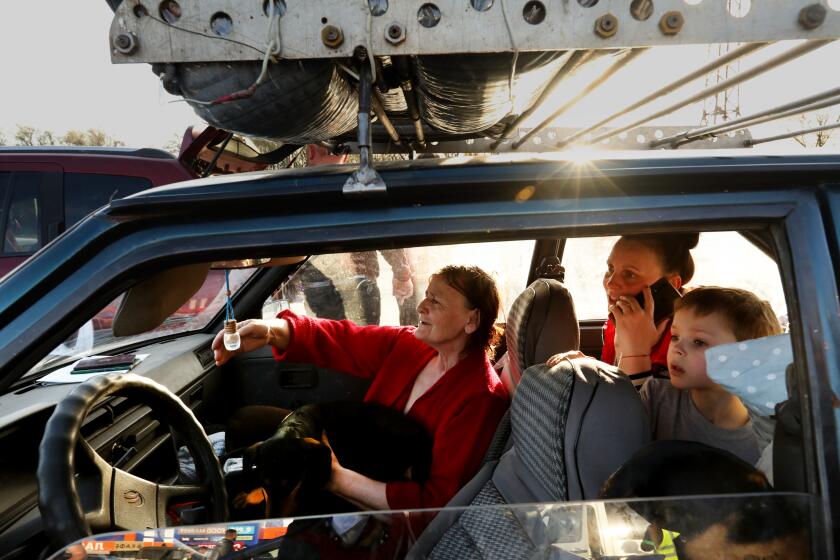 Zaporizhzhya, Ukraine-April 25, 2022-Katerina Gubochkkna, left, holds one of two Dachshunds as her and her daughter, Oksana Strishko, middle, and her son Dima Strishko, age 5, arrive from Russian occupied territory town of Vasilyevak to Zaporizhzhia on April 25, 2022. Families escaping Mariupol and other Russian occupied areas arrived at the eastern edge of Zaporizhzhia on April 25, 2022. They had endured days of bombing. (Carolyn Cole / Los Angeles Times)