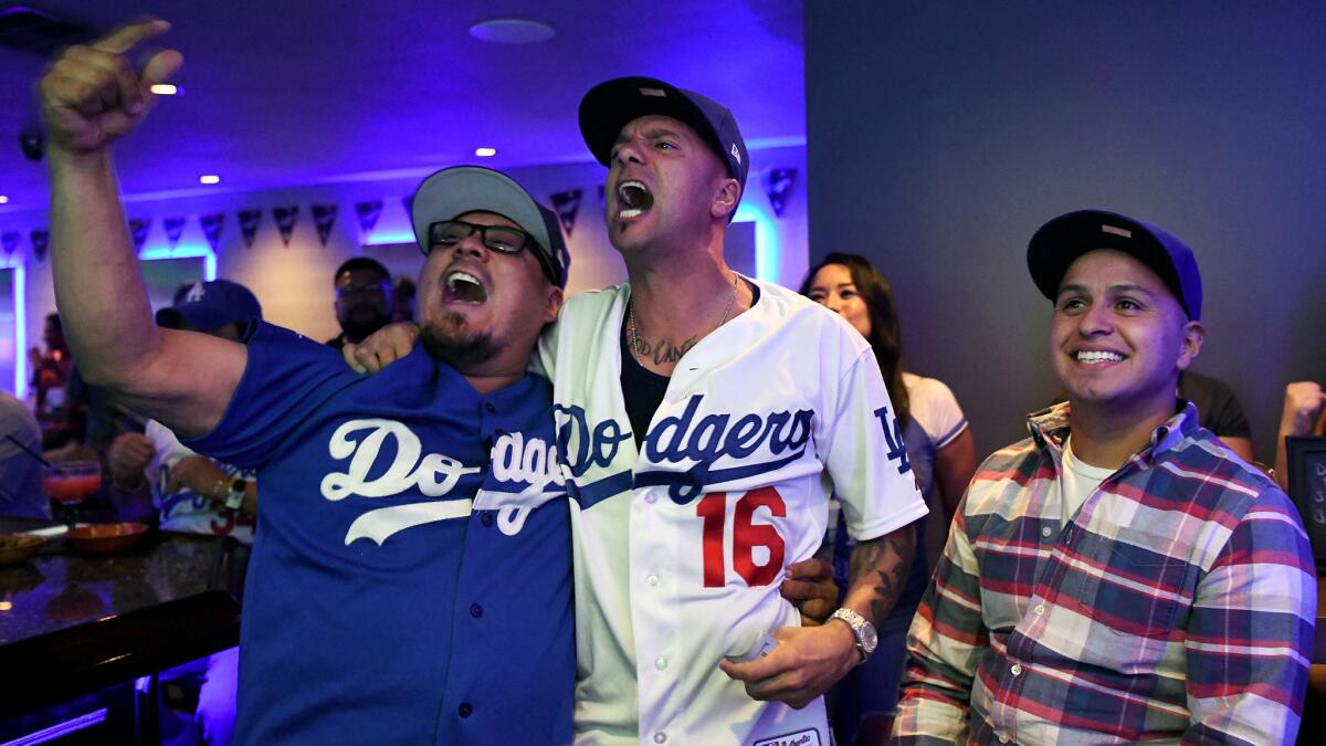 Friends Rick Ortiz, left, Ricardo Jaquez and Marco Villa cheer in the Gold Room during Game 2.