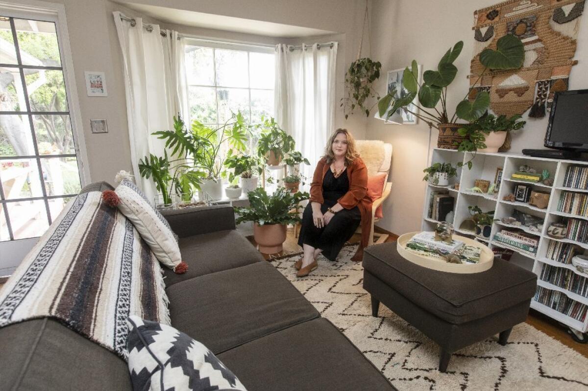 Plant expert Danae Horst sits next to a bay window full of plants.
