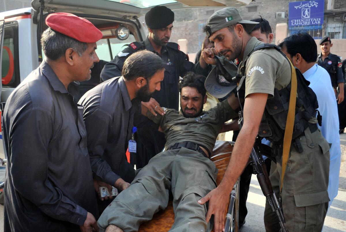 Pakistani security personnel help an injured comrade after a Taliban attack on an air base in Peshawar on Sept. 18.