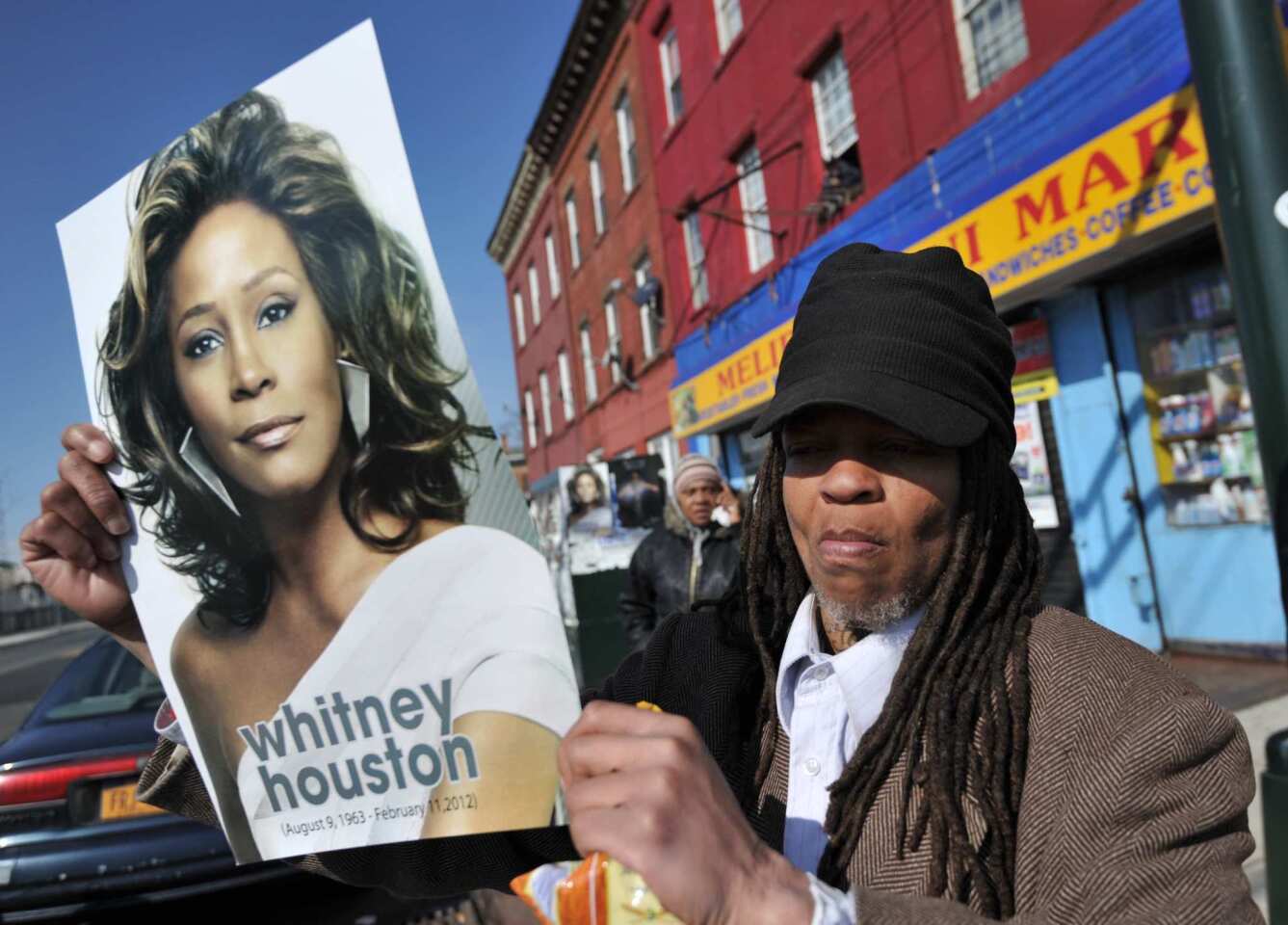 A woman carries a poster of Whitney Houston not far from the New Hope Baptist Church in Newark, N.J.