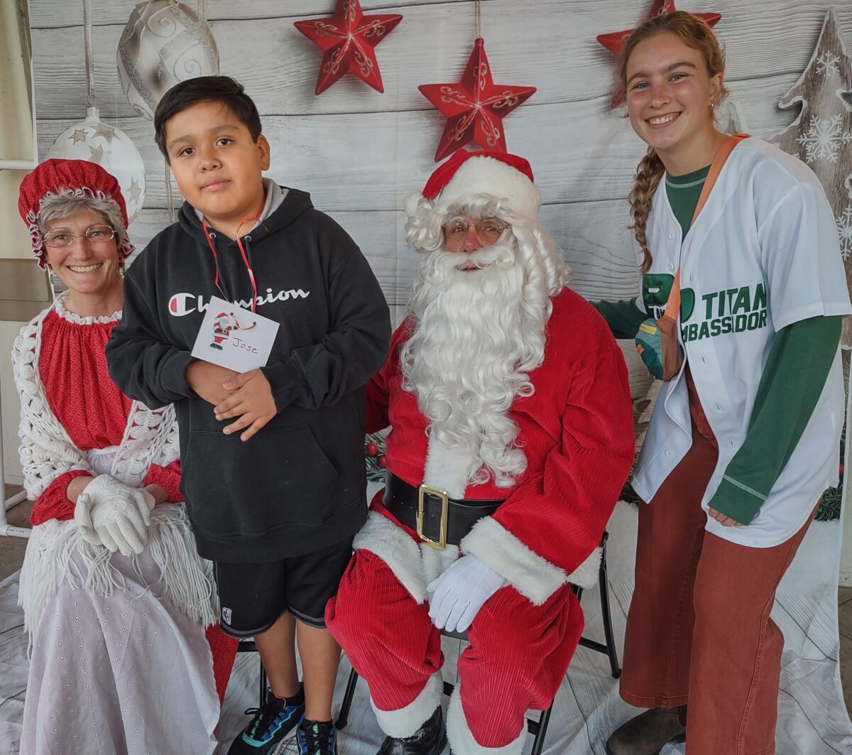 Jose Martinez, left, and his hero, Anjolie Norton, pose for a picture with Santa and Mrs. Claus.