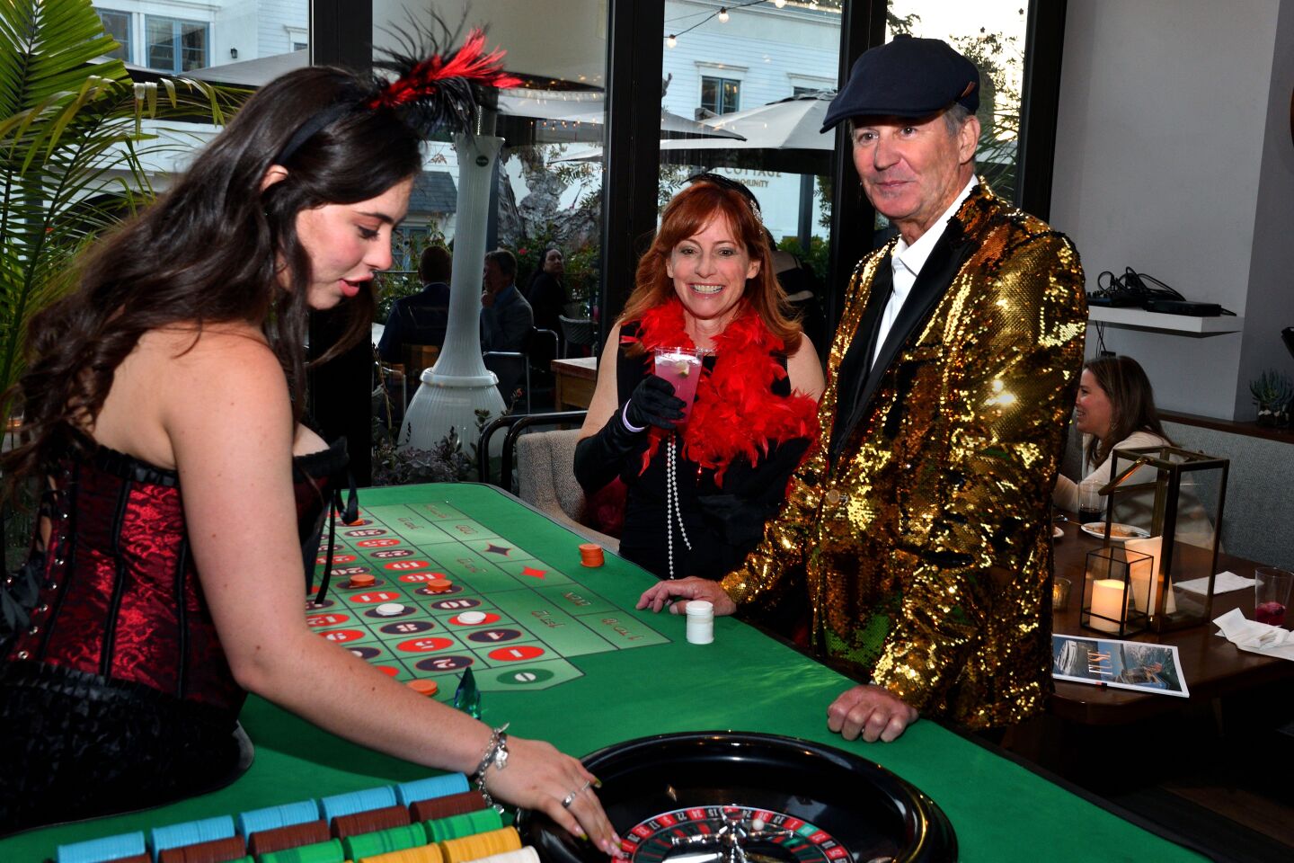 Emily Rae spins a roulette wheel for Suzanne Kelley and Loc Waders at the “Le Cabaret du Concours” cocktail party.