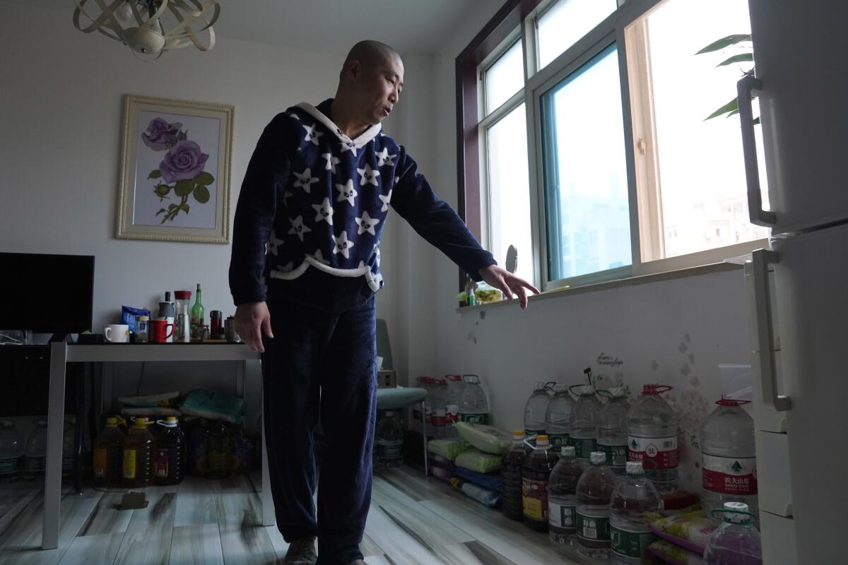 Zhu Tao of Wuhan, China, points to his stockpile of supplies in his home.