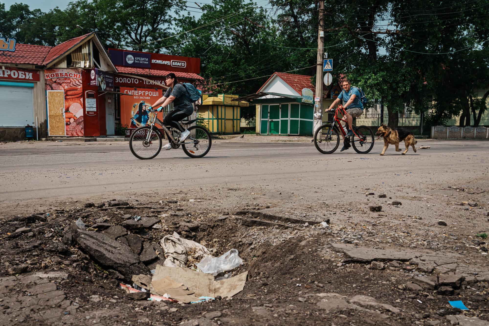 People ride bikes on a torn-up street    