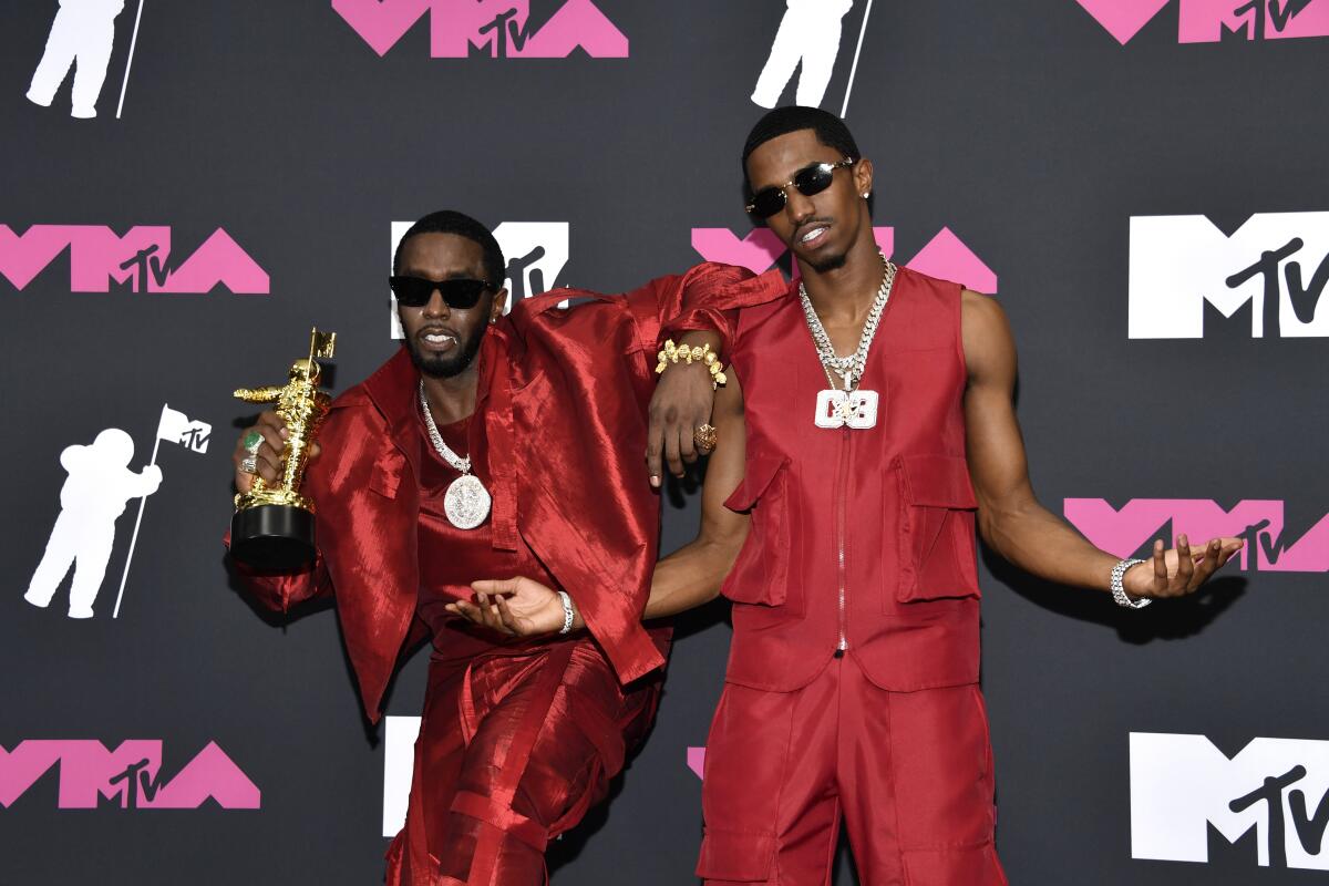 Sean "Diddy" Combs, left, and son Christian "King" Combs pose in red ensembles and bling as Diddy holds a trophy