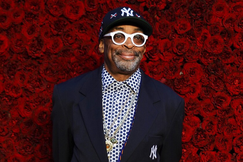 Spike Lee standing in front of a wall of red flowers