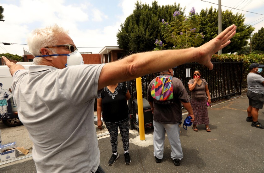 Craig Taubman directs people to wait in a line for a food giveaway for needy residents at the Pico Union Project.