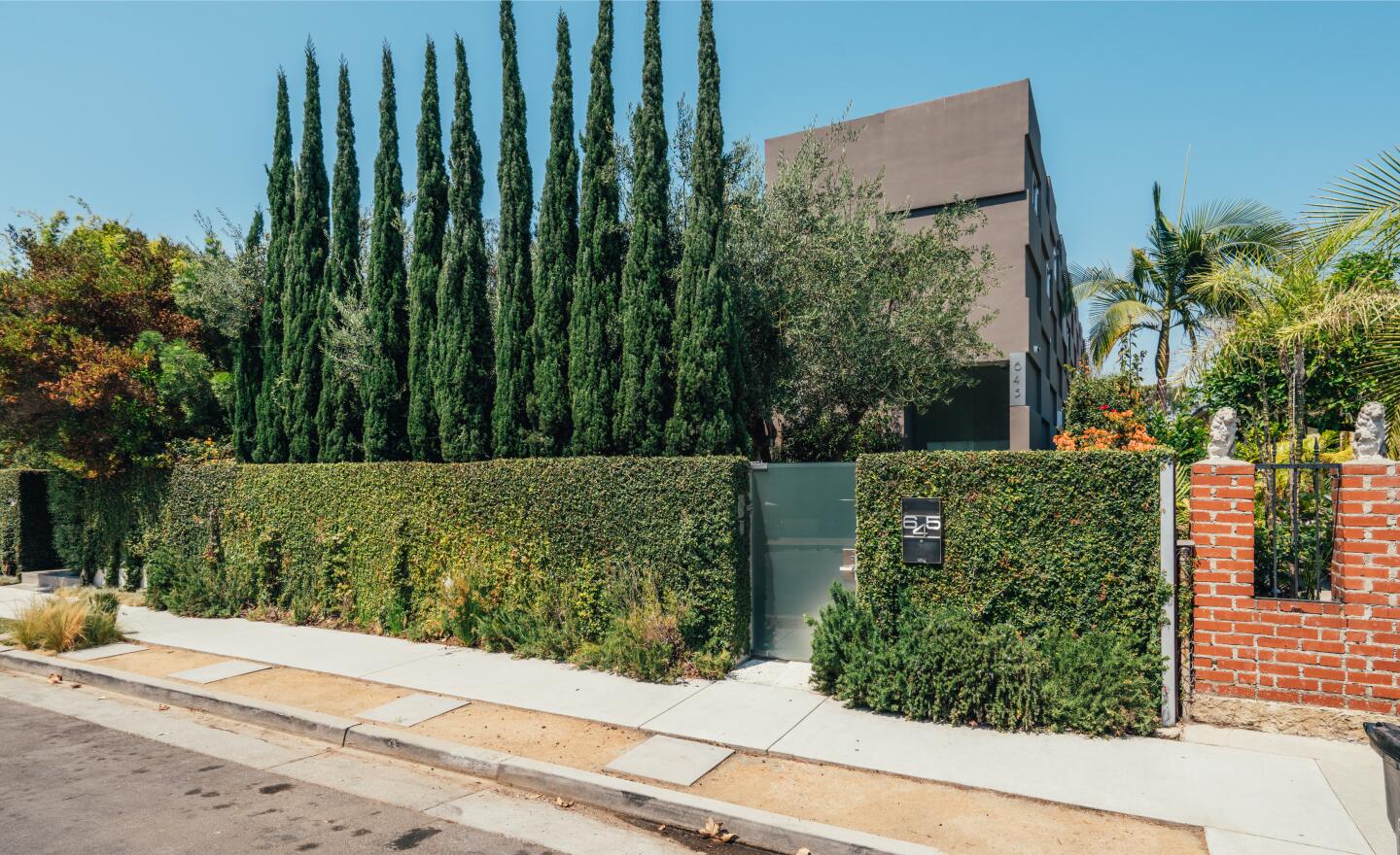 The exterior from the street shows part of the house, shrubbery and tall trees.