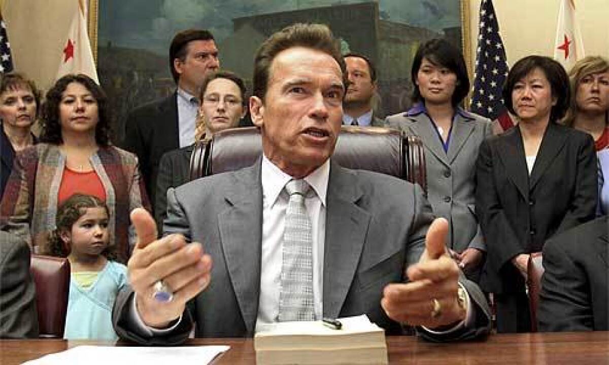 Schwarzenegger discusses the $85-billion revised state budget before signing it at the Capitol on Tuesday.