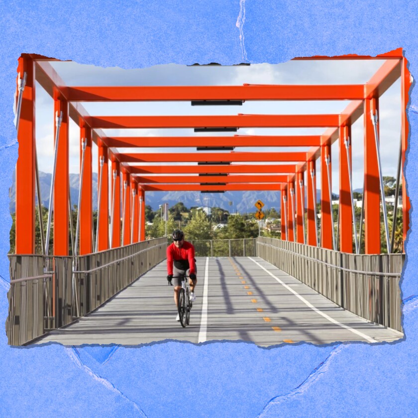 A cyclist rides across a bridge under orange girders..