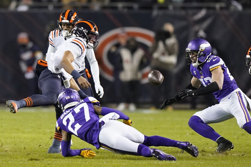 Chicago Bears quarterback Justin Fields, left, fumbles the ball as Minnesota Vikings cornerback Cameron Dantzler (27) and Xavier Woods close in during the first half of an NFL football game Monday, Dec. 20, 2021, in Chicago. (AP Photo/Nam Y. Huh)