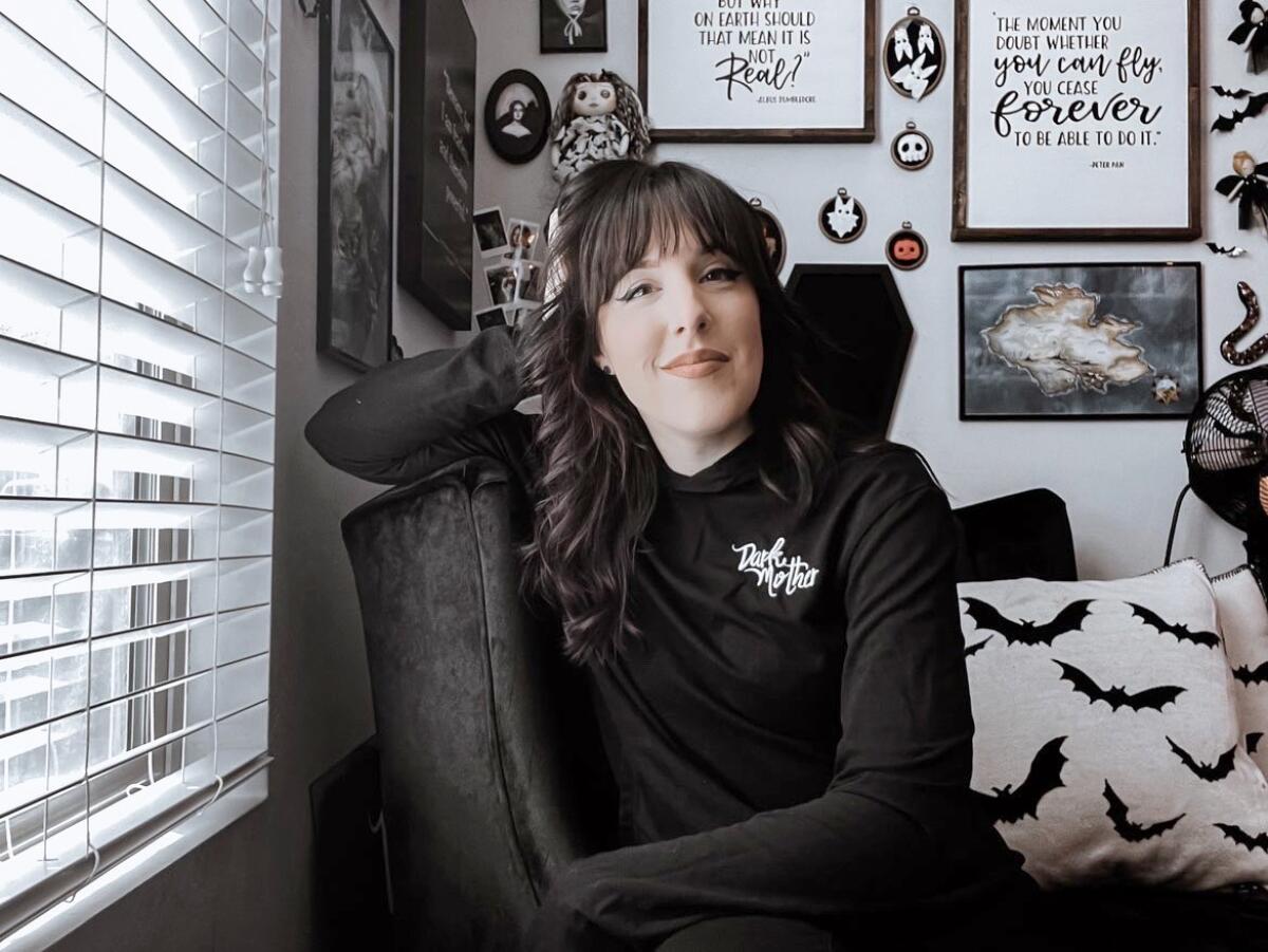 A woman dressed in black sits in a black chair.