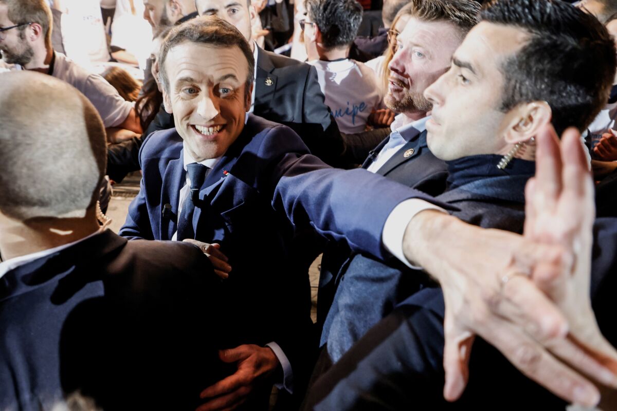 FILE -French President Emmanuel Macron and centrist candidate for reelection shakes hands with supporters as he arrives for a meeting in Paris, on April 2, 2022. President Emmanuel Macron is the clear favorite in the French presidential race. Yet a big unknown factor may prove decisive: an unprecedented proportion of people say they are unsure who to vote for or don't intend to vote at all, bringing uncertainty over the election. (Ludovic Marin, Pool via AP, File)