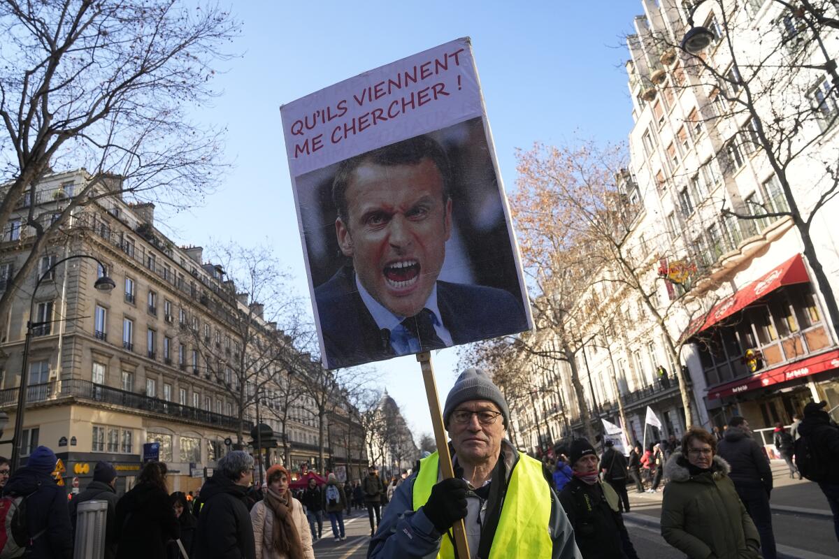 A protester holds a portrait of French President Emmanuel Macron reading "Let them come get me" during a demonstration against plans to push back France's retirement age, Tuesday, Feb. 7, 2023 in Paris. The demonstration comes a day after French lawmakers began debating a pension bill that would raise the minimum retirement from 62 to 64. The bill is the flagship legislation of President Emmanuel Macron's second term. (AP Photo/Michel Euler)