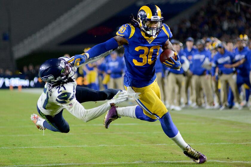 LOS ANGELES, CALIFORNIA - DECEMBER 08: Running back Todd Gurley #30 of the Los Angeles Rams stiff arms cornerback Tre Flowers #21 of the Seattle Seahawks on his way to a touchdown in the fourth quarter of the game at Los Angeles Memorial Coliseum on December 08, 2019 in Los Angeles, California. (Photo by Meg Oliphant/Getty Images)