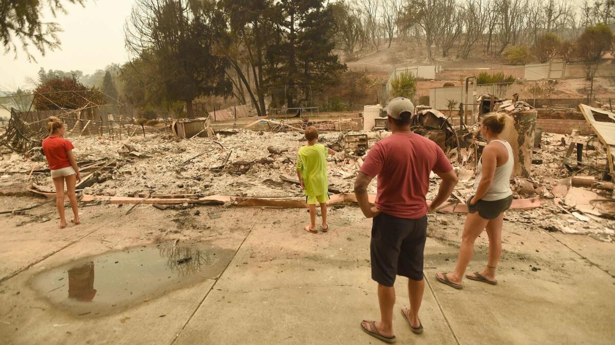 Wade Brilz looks at his burned home with his family during the Carr fire in Redding, Calif.
