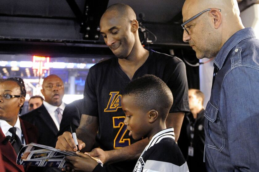 Lakers forward Kobe Bryant signs an autograph for a young fan as he walks off the court following a game against the Nets.
