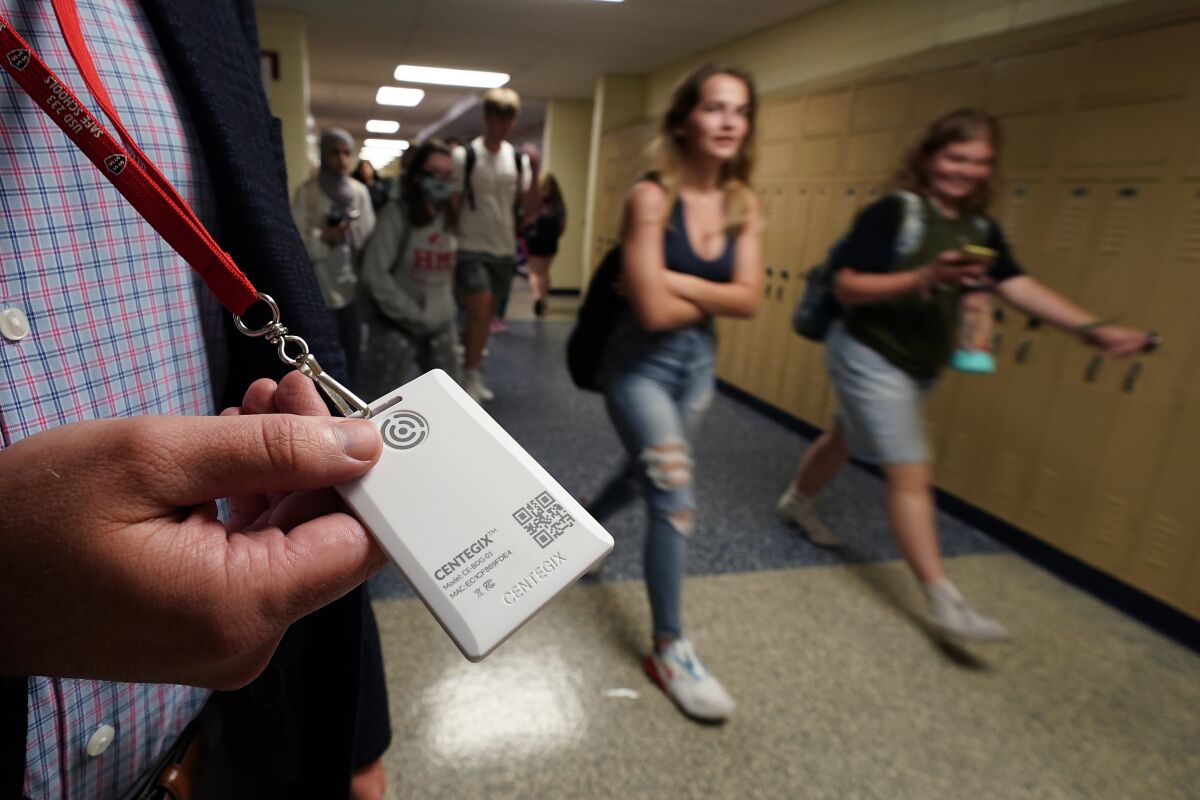 Brent Kiger, Olathe Public Schools' director of safety service, displays a panic-alert button while students at Olathe South High School rush between classes Friday, Aug. 19, 2022, in Olathe, Kan. The district introduced the buttons, which allow staff to trigger a lockdown that will be announced with flashing strobe lights, a takeover of staff computers and a prerecorded intercom announcement, at the start of this school year as part of $2.1 million plan to make district schools more secure. (AP Photo/Charlie Riedel)