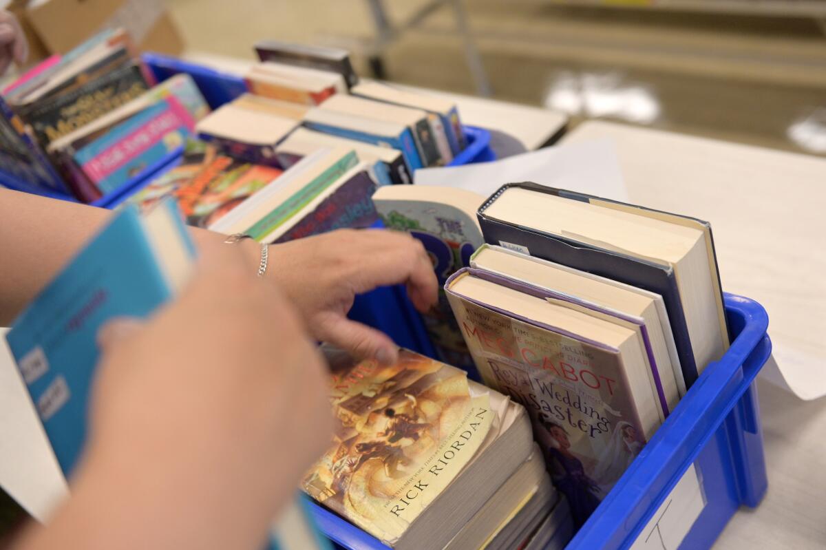 Hands sorting through stacks of library books