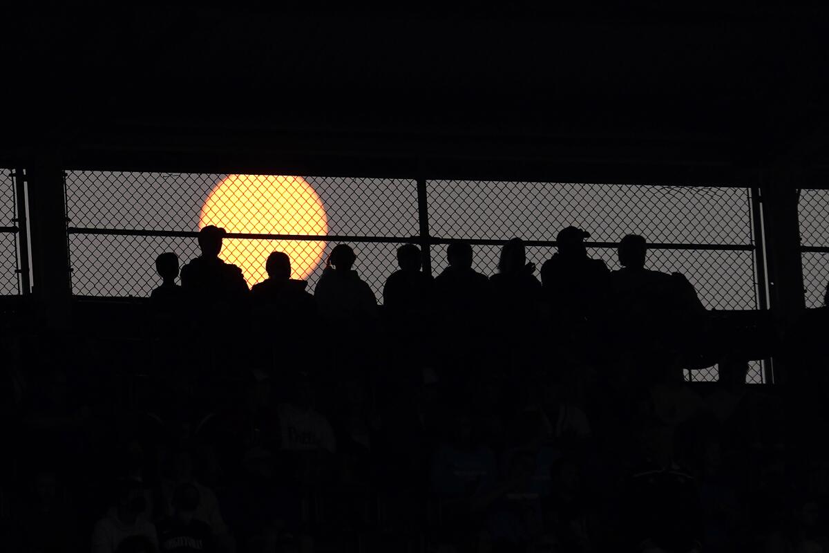 Silhouettes of people against setting sun at Wrigley Field in Chicago