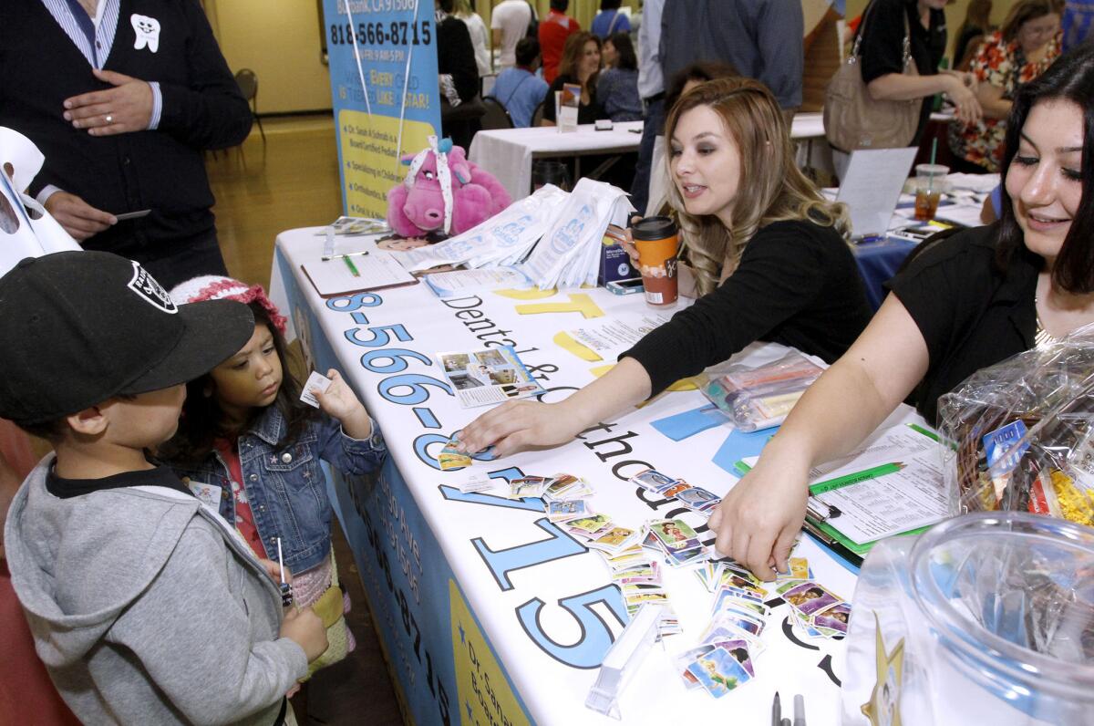 Star Kids Dental's Brittany Acebal, center, offers stickers to children at the Glendale Health Festival at the Civic Auditorium in Glendale on Saturday, Nov. 2, 2013.