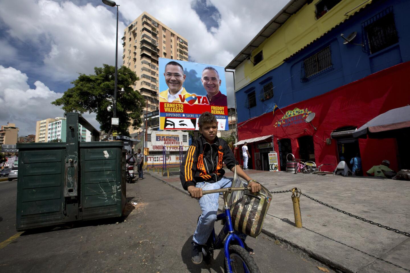 Un niño pasa en bicicleta frente a un cartel de candidatos oficialistas a las elecciones legislativas en Caracas, Venezuela, 4 de diciembre de 2015.