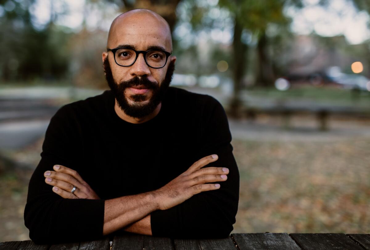 A man in a black shirt sits with his arms crossed.